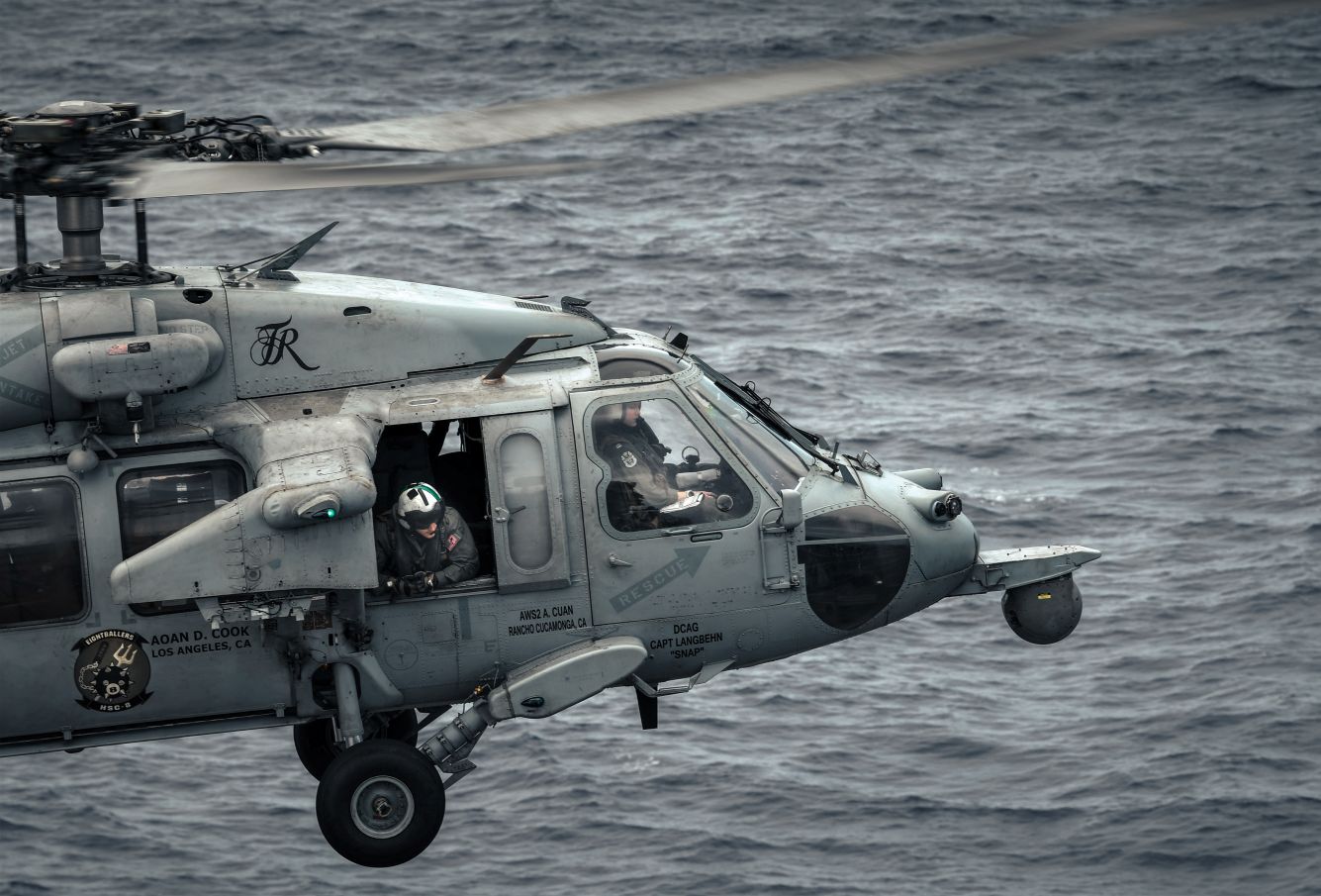 MH-60 helicopter flying over the flight deck in the Pacific Ocean